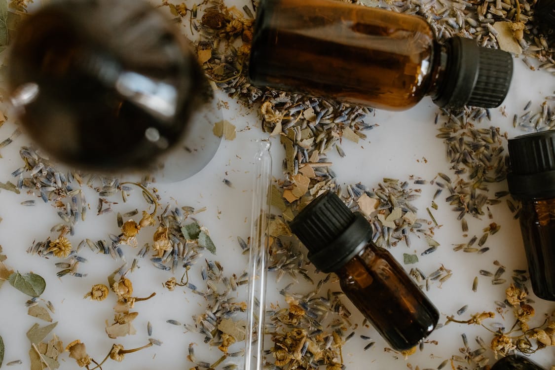 Free Close-Up Shot of Essential Oil Bottles and Medical Herbs on White Surface Stock Photo