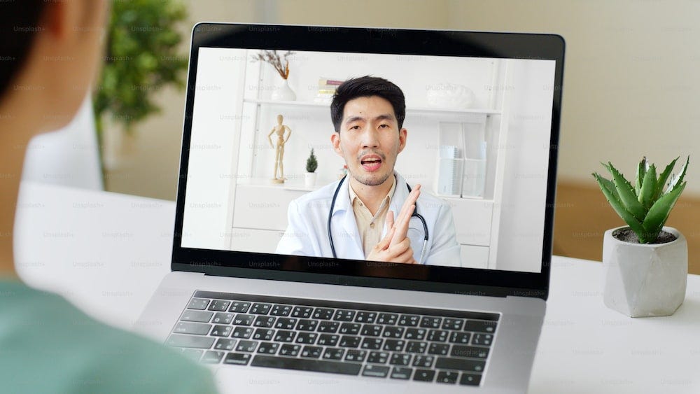 Asian woman talking with doctor via computer laptop virtual video call or video conference at home, telehealth and telemedicine concept Asian woman talking with doctor via computer laptop virtual video call or video conference at home, telehealth and telemedicine concept