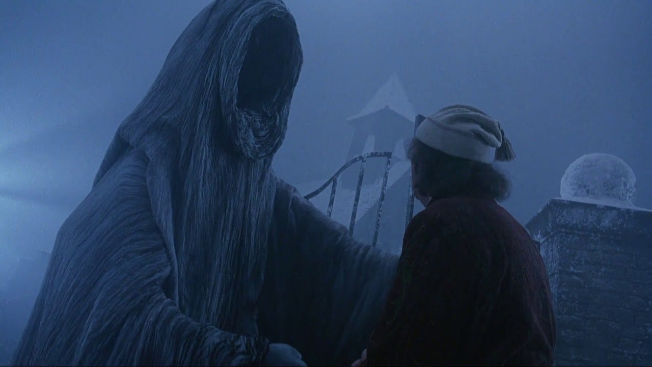 A tall faceless figure in a gray cloak extends its arms toward a shorter person with gray hair wearing a stocking cap. They are standing in a snowy cemetery.