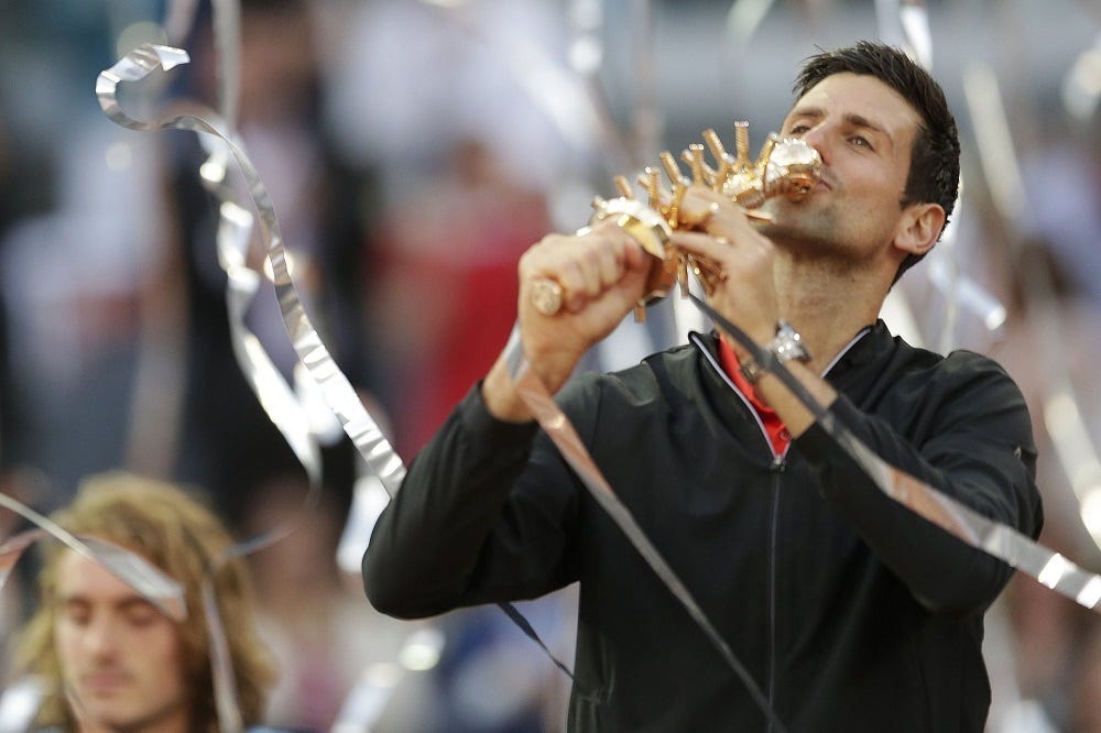 novak djokovic kisses 2019 madrid open title with stefanos tsitsipas sits behind him