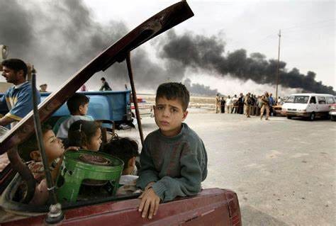 a 2004 photo of young iraqi children in the back of a car, as fires rage behind them