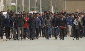 Migrants carrying sticks march in the streets of Calais, northern France.