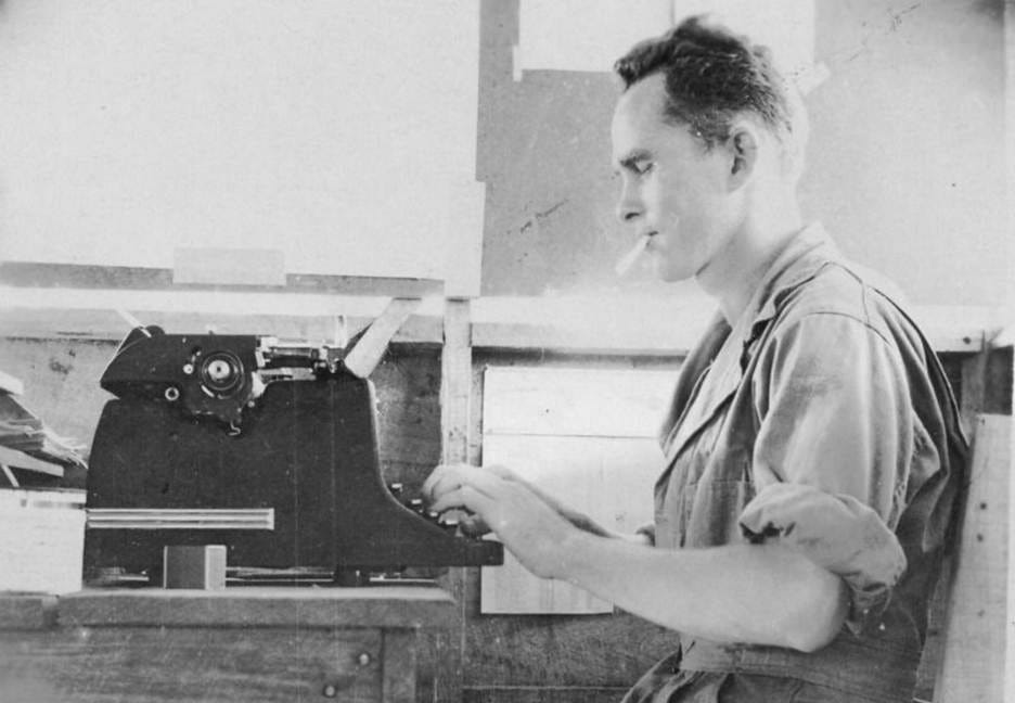 A person sitting at a desk using a typewriter

Description automatically generated