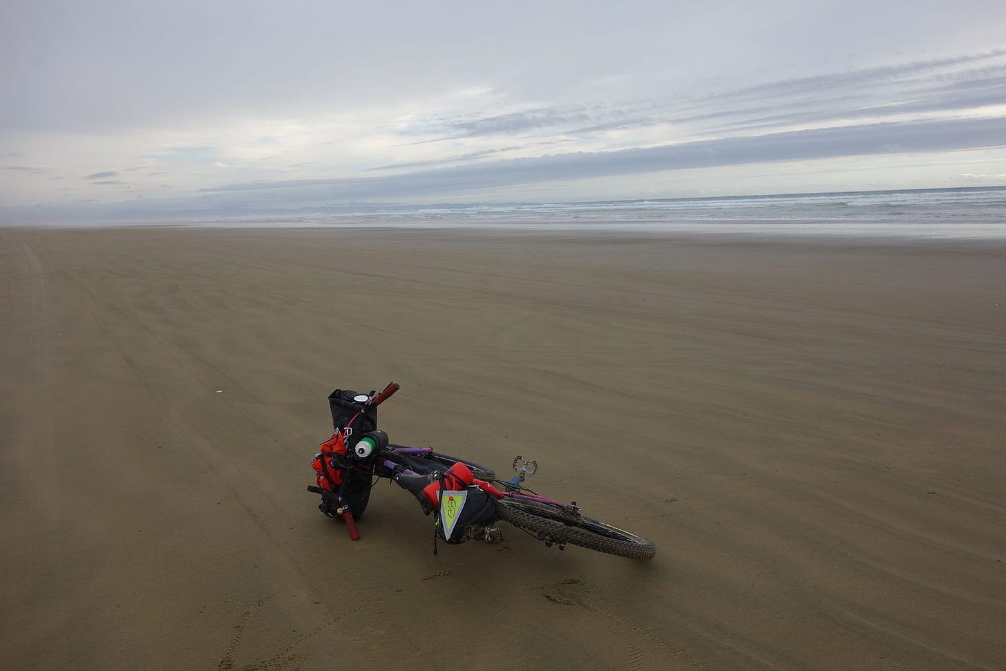 The bicycle is on the sand in the open expanses of ninety mile beach.