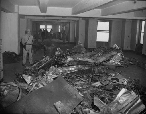 En militær politimann, til venstre, vokter vrakingen av en B-25 Bomber etter at det lavtflygende flyet styrtet gjennom nordveggen i 79. etasje i Empire State Building i New York City, 28. juli 1945. Andre tjenestemenn og arbeidere sees i bakgrunnen.