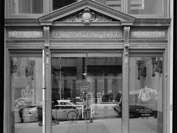 A black-and-white photograph of the front entrance to the Baltimore & Ohio office building in downtown Baltimore. Over the door it states: "BALTIMORE & OHIO RR."