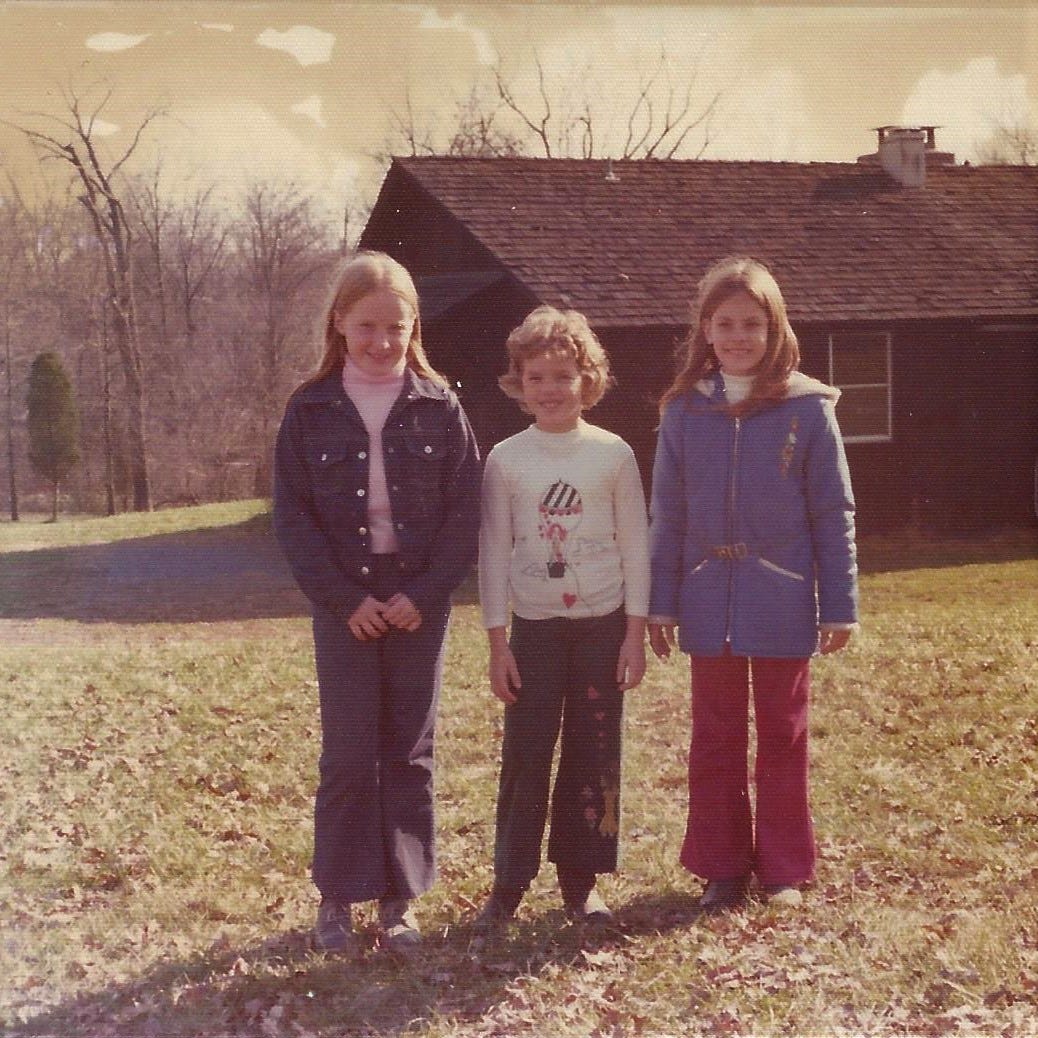Three 9-year-old girls standing outside a cabin at Girl Scout camp