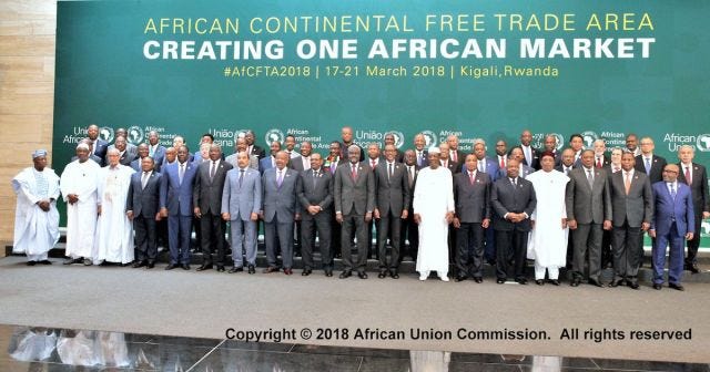 Approximately 50 ministers and heads of state, all male, stand in front of a sign which says "African continental free trade area"