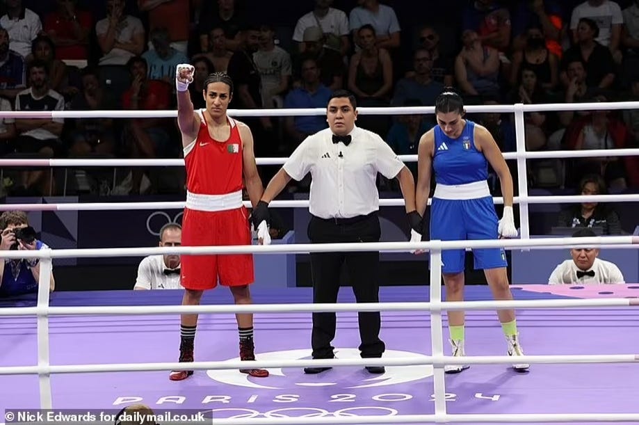 Imane Khelif, who failed a gender eligibility test, towers over Angela Carini as the referee raises his hand in victory, symbolizing a profound injustice and the madness of allowing male athletes to compete against women. This moment exemplifies the larger design to undermine Western culture.