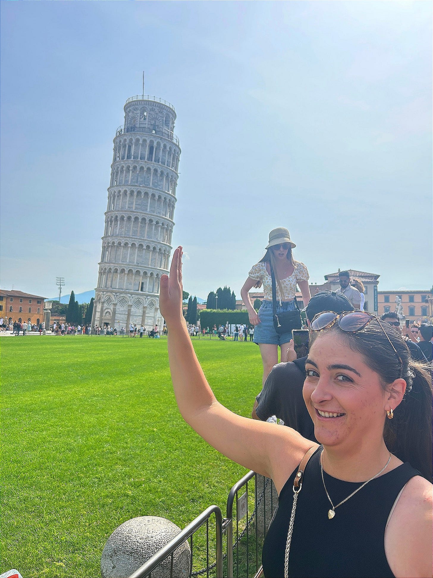 Young woman posed so that it appears that she's supporting the leaning Tower of Pisa