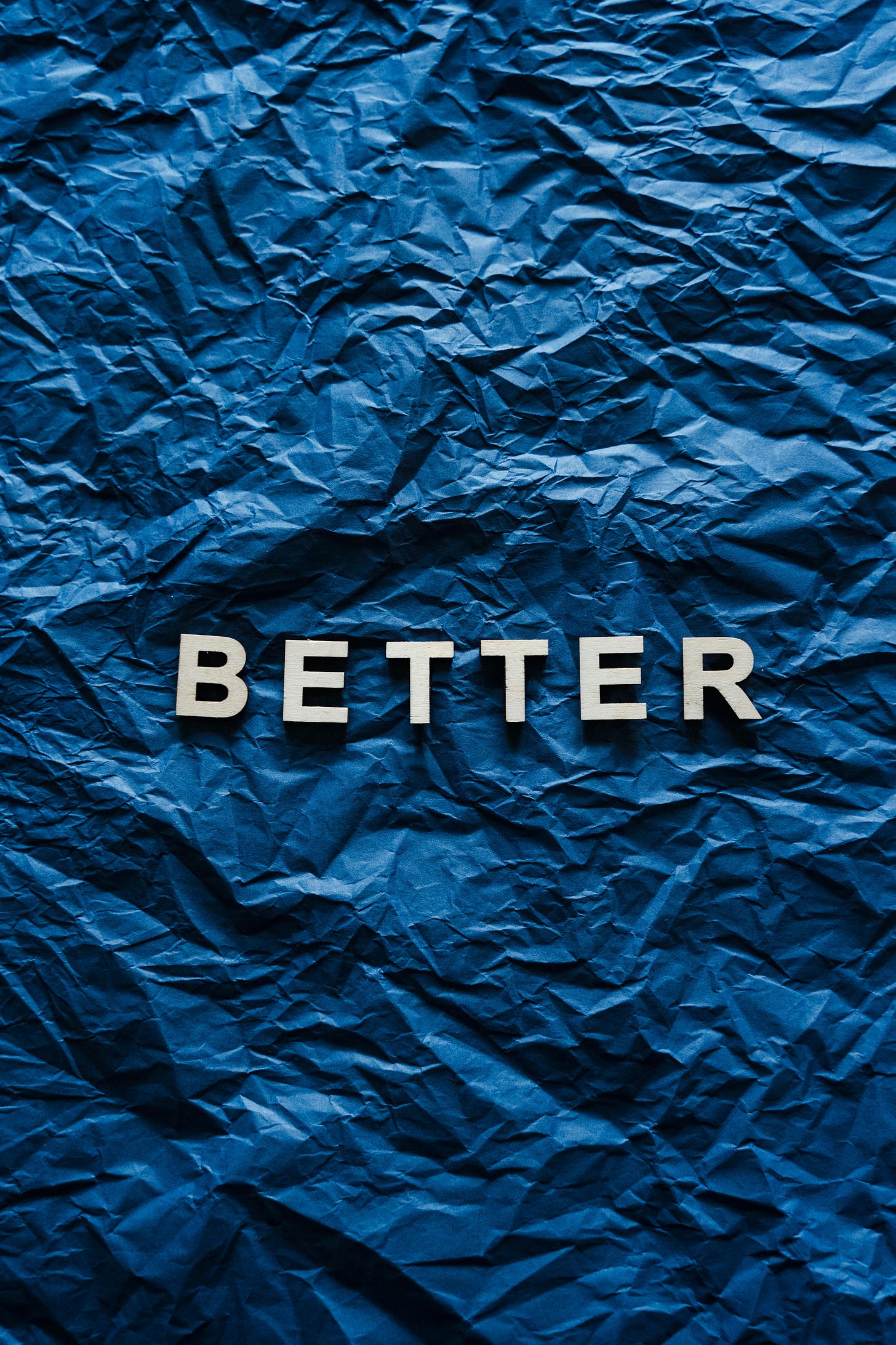 The word Better on a dark blue background of crinkled paper.