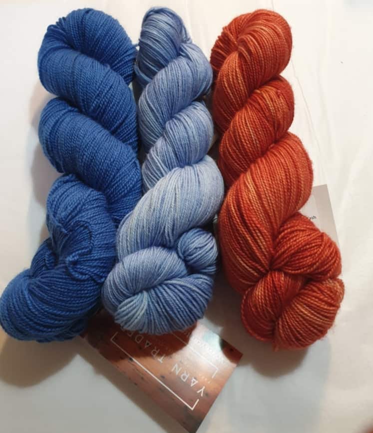 Yarn Trader Studio Skinny Sock Yarn from left to right Electric City (electric blue color), Caladan Waters (sky blue color), Coral (burnt orange color)