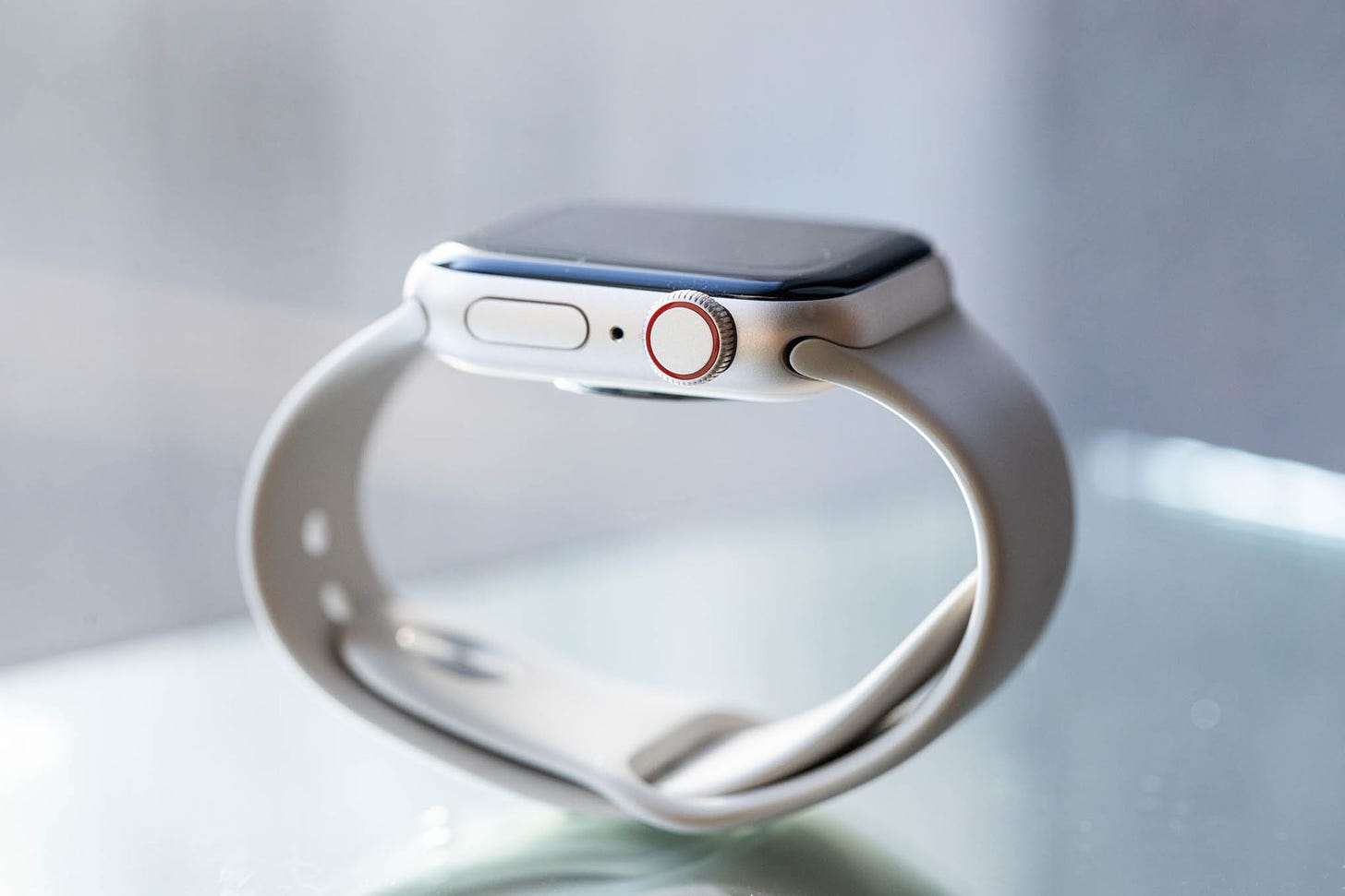 A picture of an Apple Watch SE balanced on its silicone band.