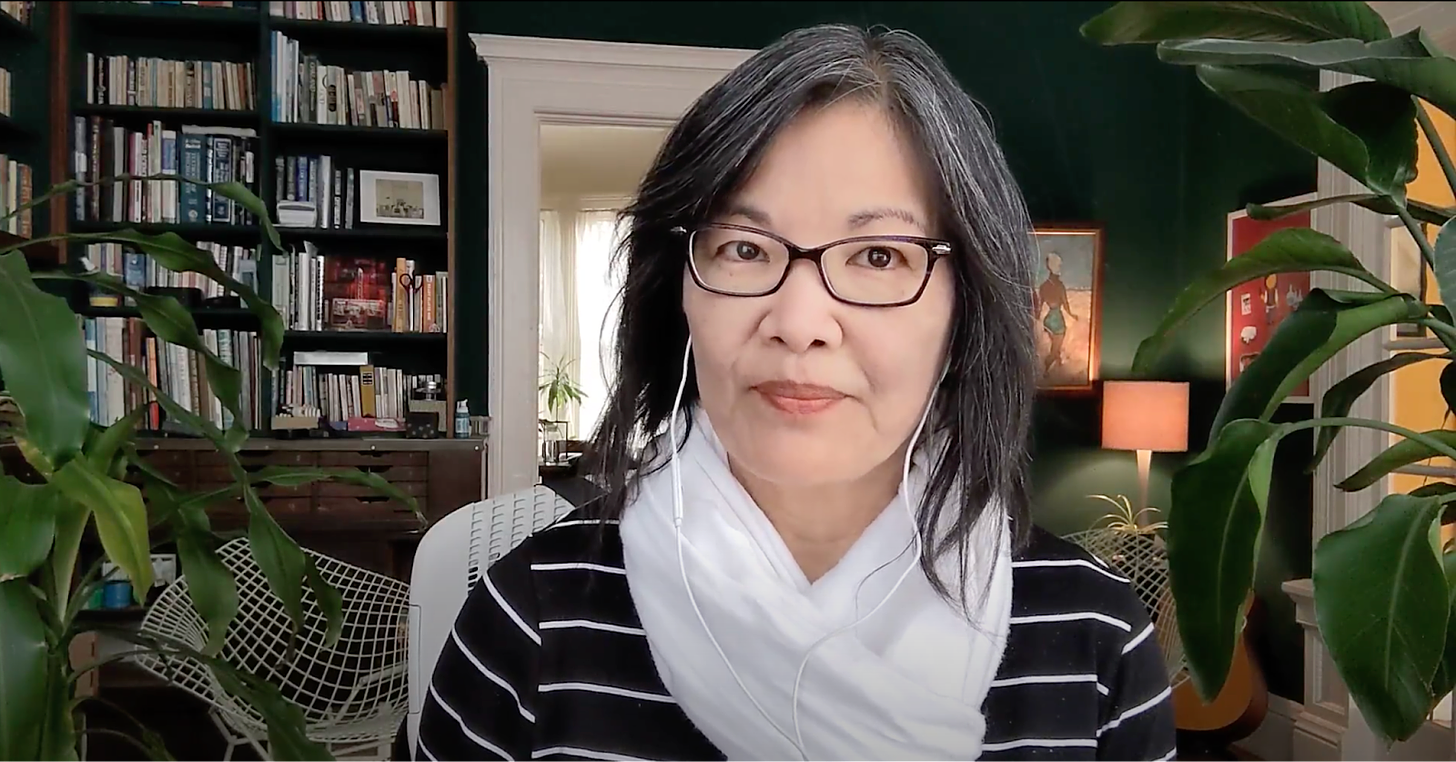 Headshot of Margaret Lee in her home office with bookshelves and plants.