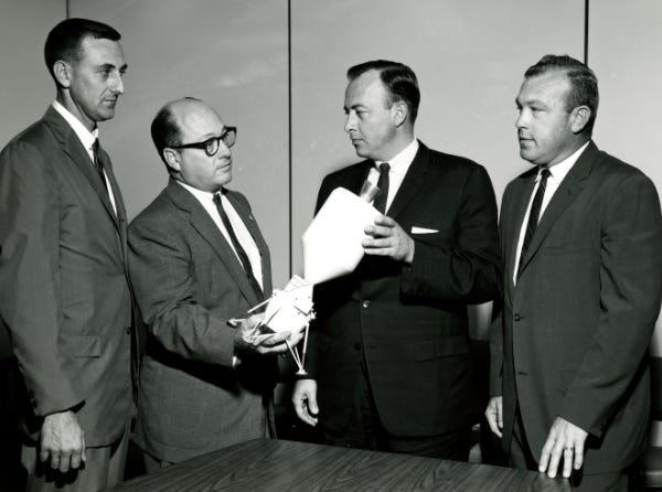 NASA modeler holding a 1962 Lunar Excursion Module concept model, together with colleagues (Credit: NASA)