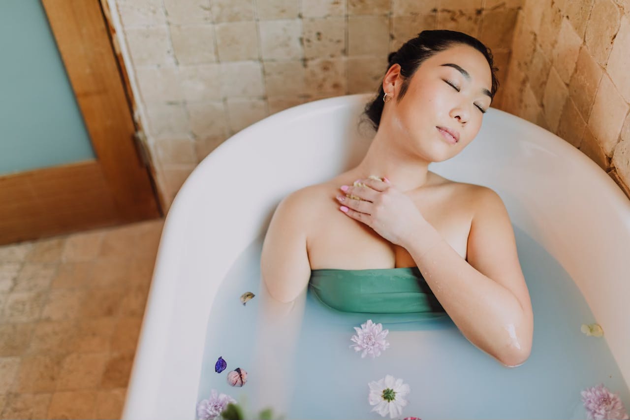 Asian woman relaxing in bathtub with eyes closed