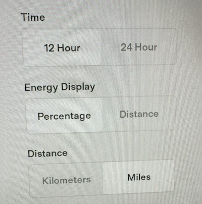A screenshot of the Tesla settings UI showing the Energy Display toggle with options of "percentage" and "distance". Some other settings are shown above and below for context.