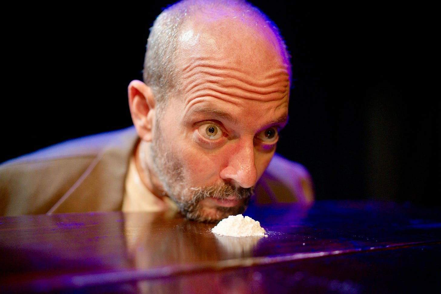 An actor portraying Sigmund Freud prepares to snort cocaine