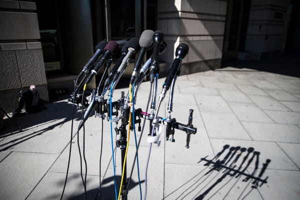 A photograph of several empty microphones casting their shadows on the ground. 