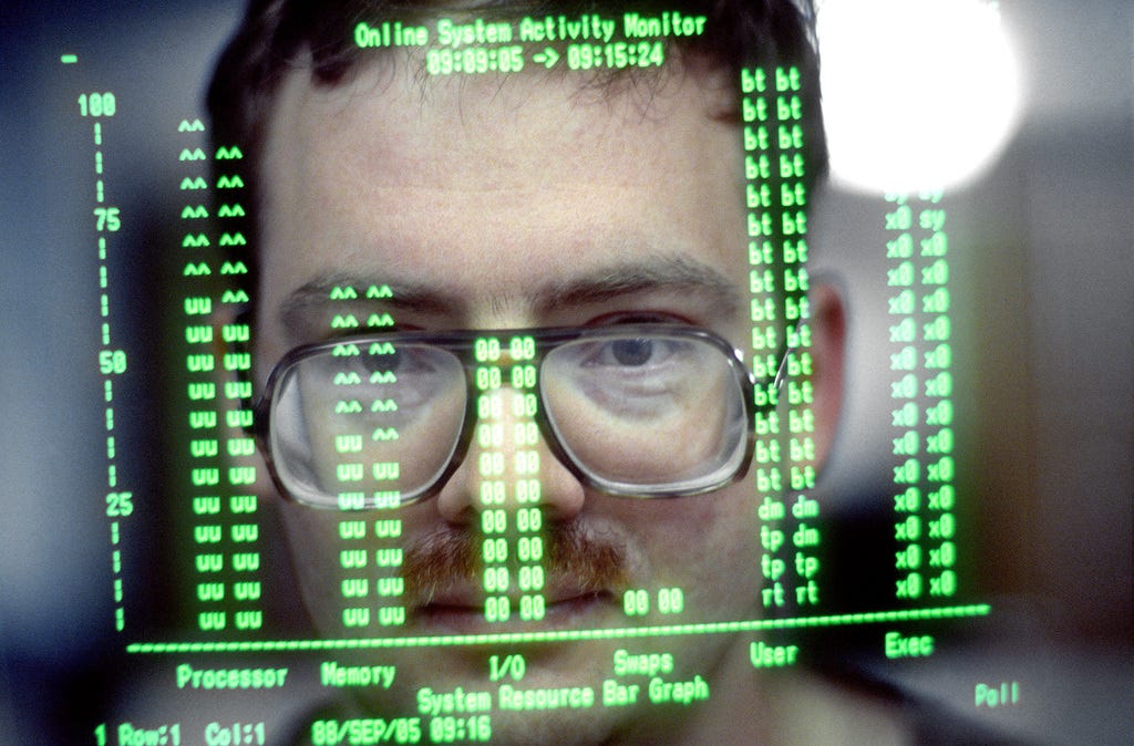The face of a computer operator from the 2134th Communications Squadron is reflected on the screen of his video display terminal (1988).