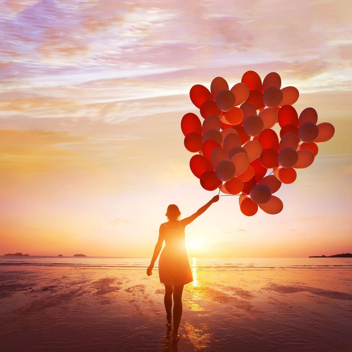 woman on a beach holding orange balloons