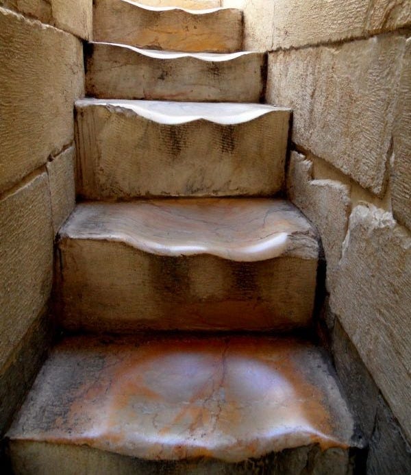 Centuries of feet eroding away the stone...?
