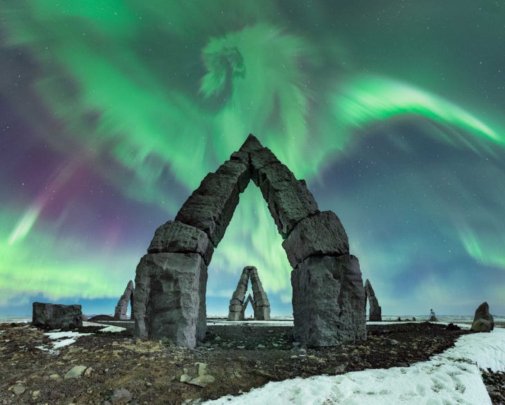 A photograph of the Northern Lights above some stone arches