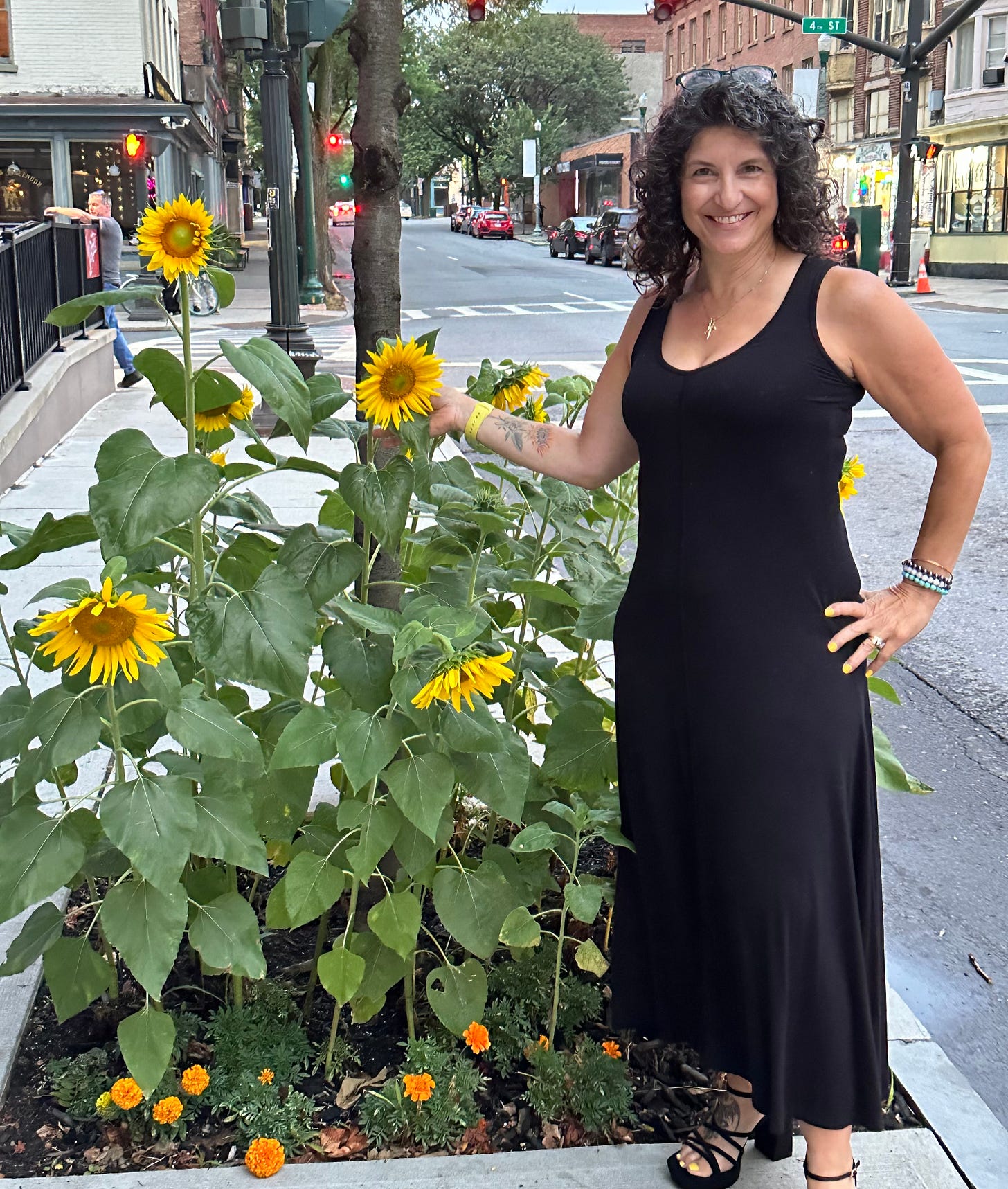 woman in black dress next to sunflowers