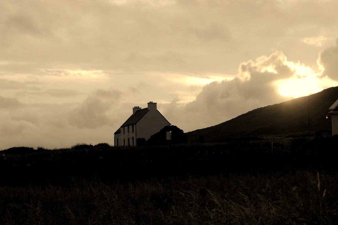 A house on a hill with a sunset in the background