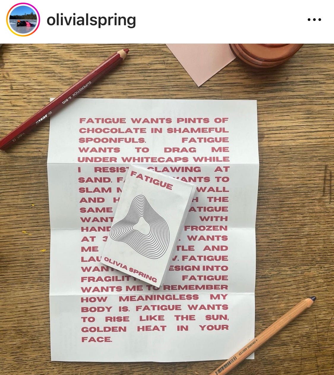 Image of an instagram post from @oliviaspring, a print of red letters on white paper that begins "Fatigue wants pints of chocolate in shameful spoonfuls" on a wood desk with a red pencil nearby.