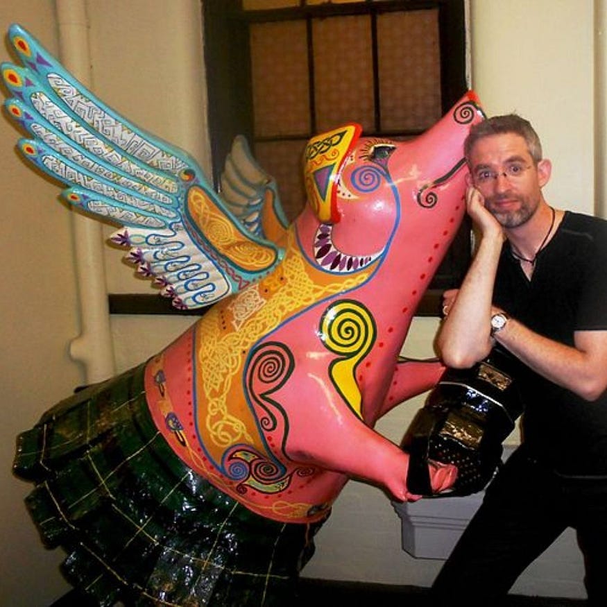 a colorful artist’s sculpture of one of Cincinnati’s flying pigs playing the concertina for Irish banjo virtuoso, Enda Scahill.