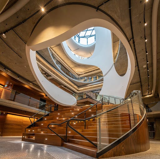 Photo shows wide curved stair case with elaborate swirly panels above it in the shape of an egg