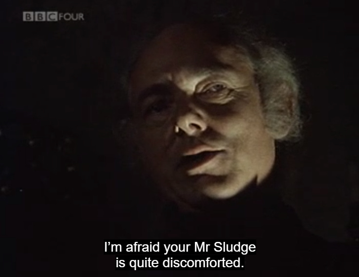 BBC still of man's face, half in darkness, saying: "I'm afraid your Mr. Sludge is quite discomfited"