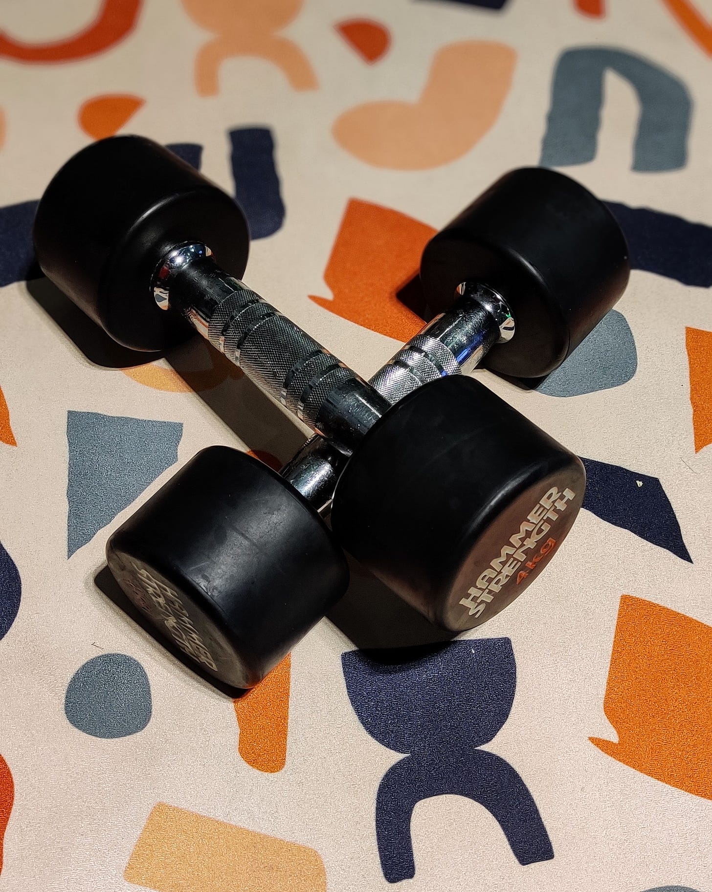 a set of dumbbells atop a patterned yoga mat