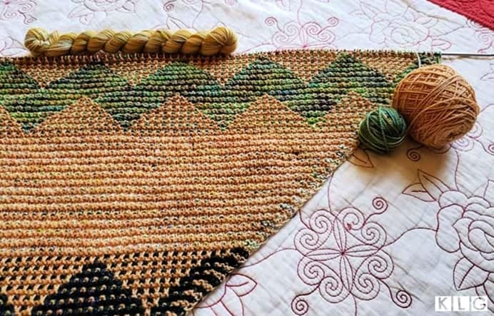 My Kentia wrap  showing the Koigu green multi colored yarn, pale caramel brown yarn and a mini skein of yarn in yellows and greens.