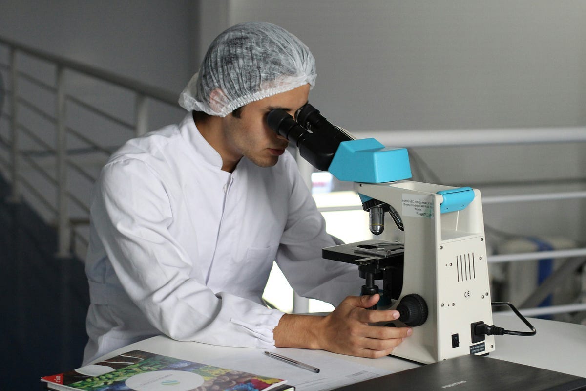 Researcher in lab, looking down microscope. Researcher in lab, looking down microscope.