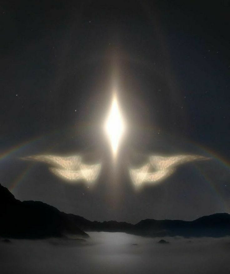 This may contain: two angel wings in the sky with a bright halo above them and mountains behind it