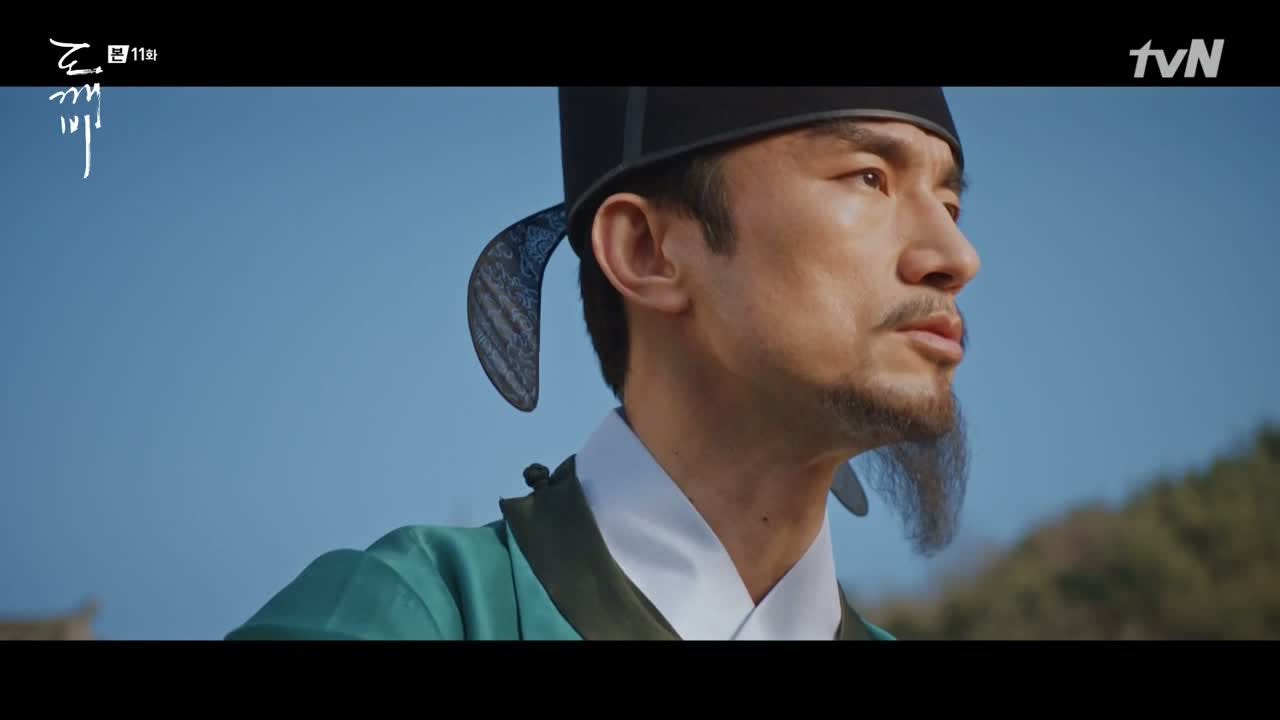 A Goryeo-era Korean eunuch looks offscreen against a cloudless blue sky