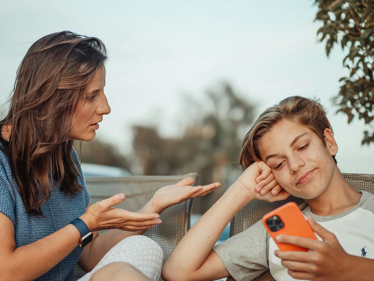 A Boy Looking at His Smartphone While His Mother is Talking · Free Stock  Photo
