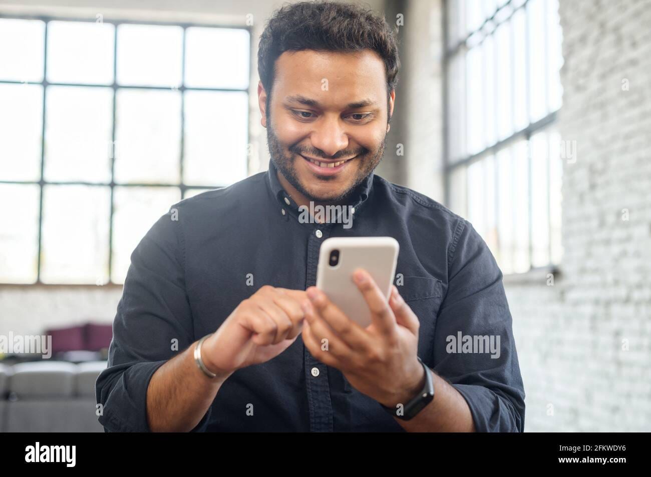 Positive indian guy using smartphone for online communication, smiling  mixed-race guy browsing, scrolling news feed, messaging in social  media,hindu man holds phone and enjoying new mobile application Stock Photo  - Alamy