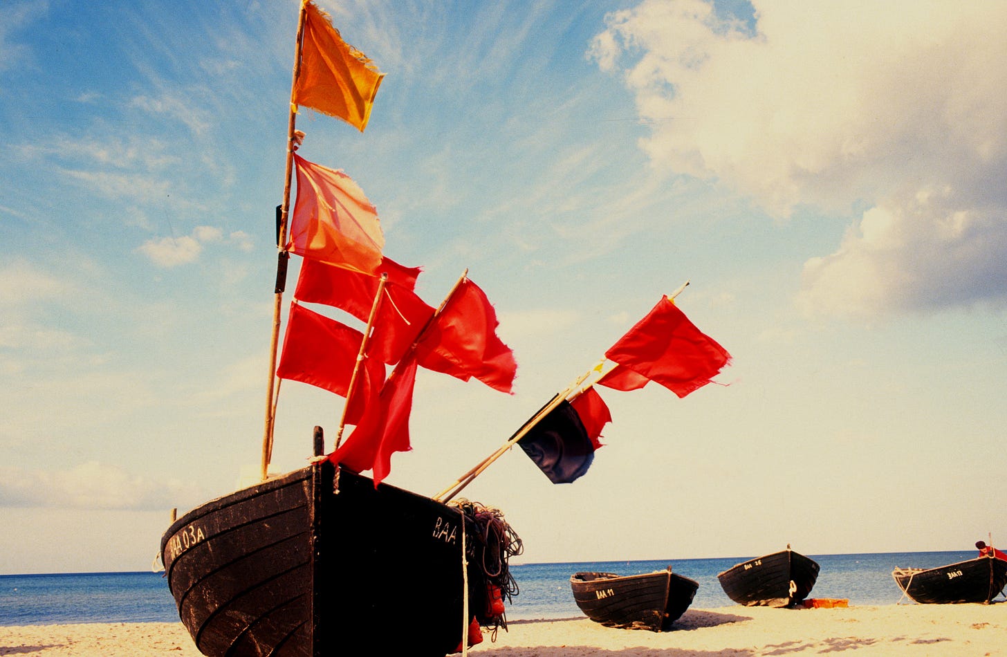 Boat on beach with red flags