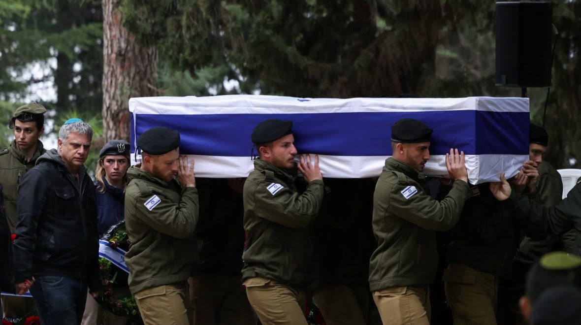 Israeli soldier hold up a casket draped in an Israeli flag.