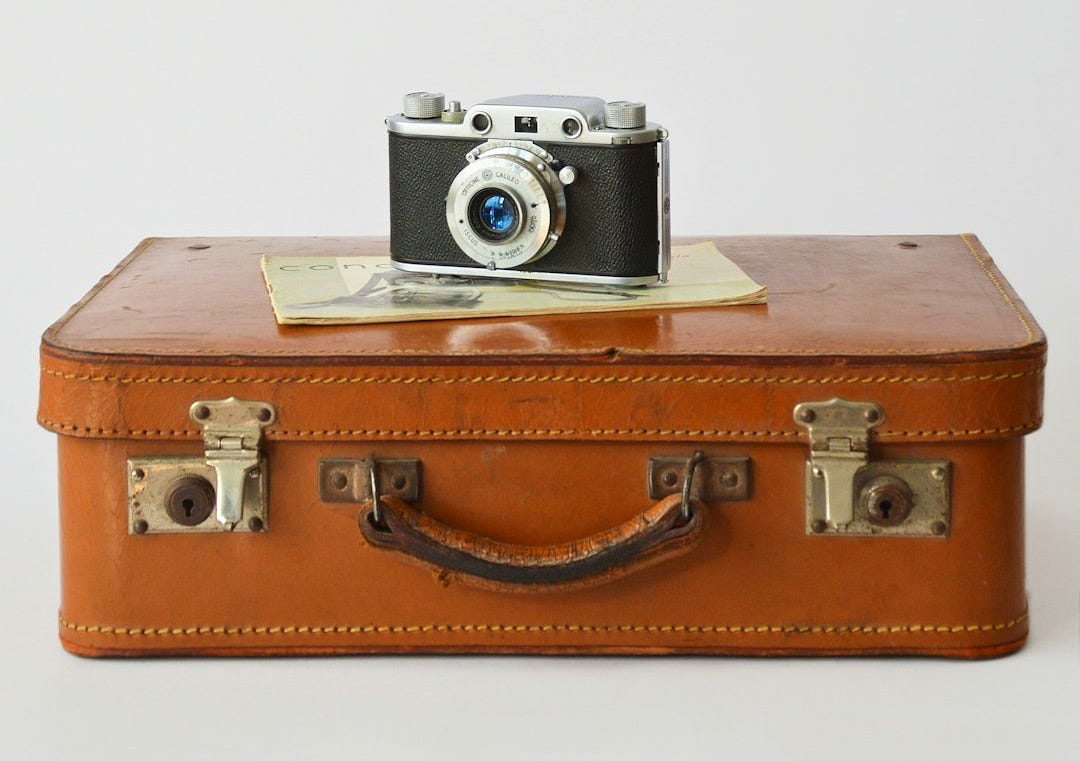 a camera sitting on top of a brown suitcase