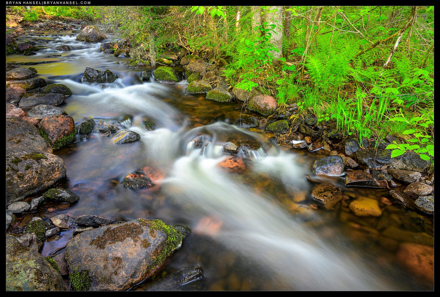 A small stream with rapids diagonals up the photo.
