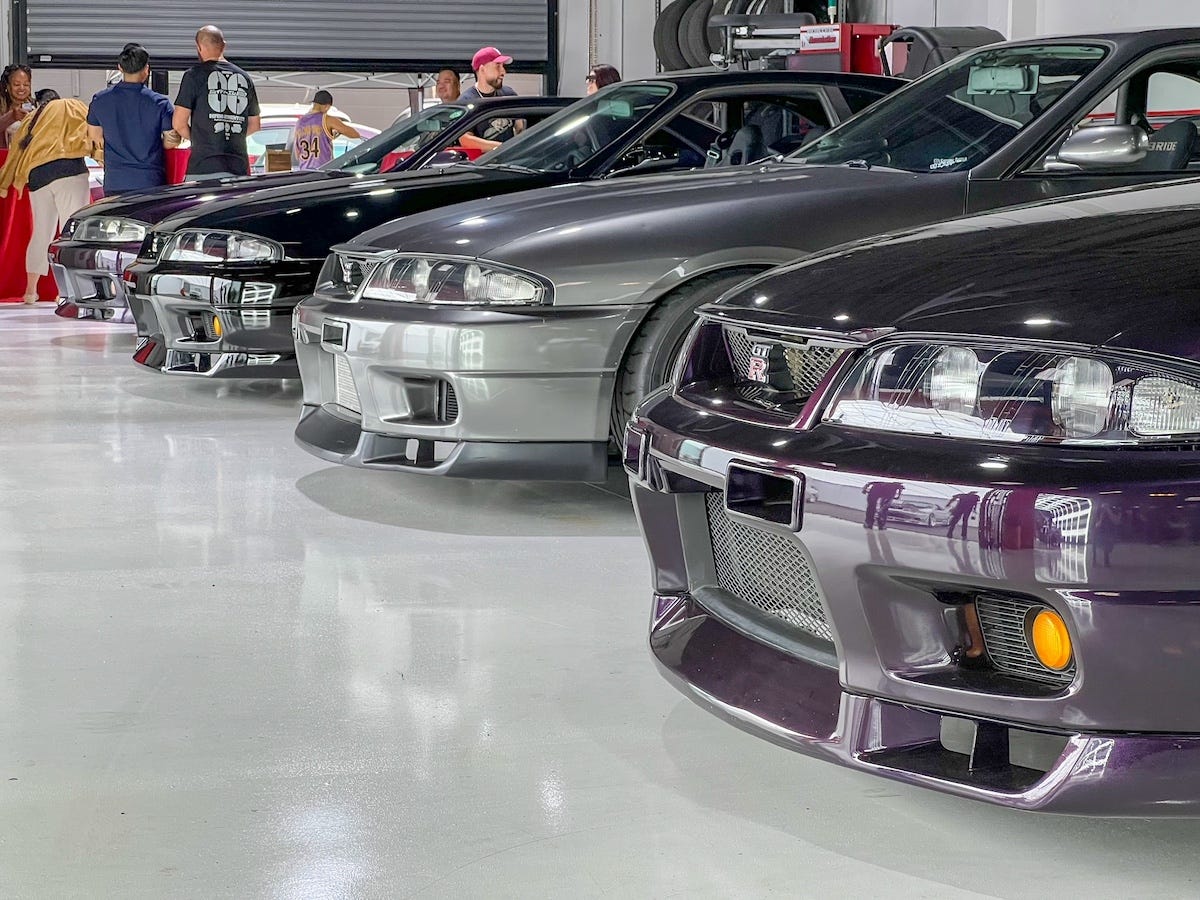 Four Nissan R33 Skyline GT-R lined up alongside one another in purple, black and silver with various aftermarket bumpers and parts. Photo by Ryan ZumMallen, author of the book "Cult of GT-R."