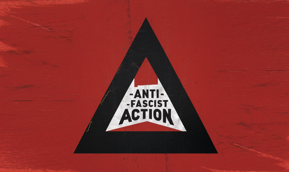 Un épais triangle noir avec écrit à ‘lintérieur “Anti-fascist Action”, sur un fond rouge moucheté de noir.