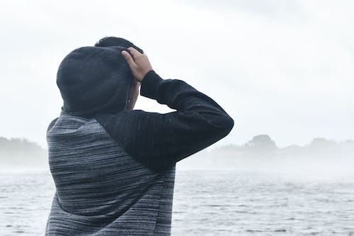 Free Person in Black and Grey Raglan Hoodie Near Body of Water Stock Photo