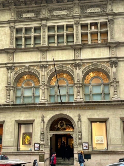 A stone building with decorative engraving. Gold lettering over the doors reads, "The Art Students League of New York." Three engraved squares under the roof read "Painting," "Architectvre," and "Scvlptvre."