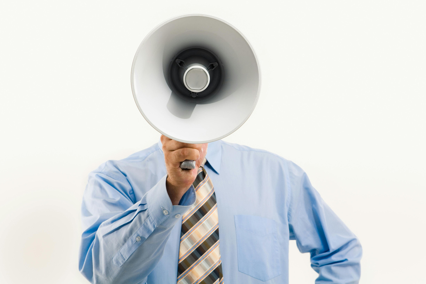 A person wearing a blue dress shirt and yellow and black tie holding a megaphone that obscures their face.
