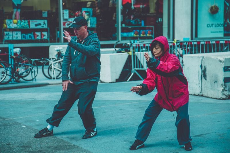 Two people practicing tai chi outdoors in a city plaza